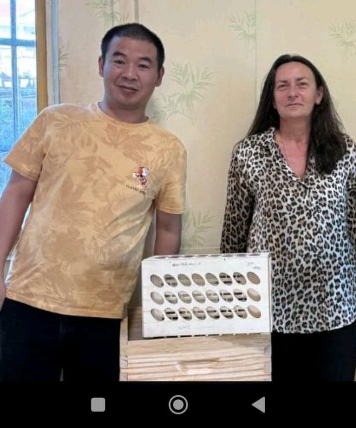 Man in yellow shirt and woman in leopard print pose behind a white wooden crate.